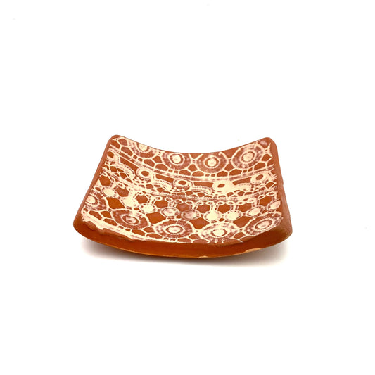 This exquisite rectangular soap dish is crafted using authentic Haitian clay, featuring a unique imprinted design and a protective top glaze, perfectly designed to hold your favorite block of soap.