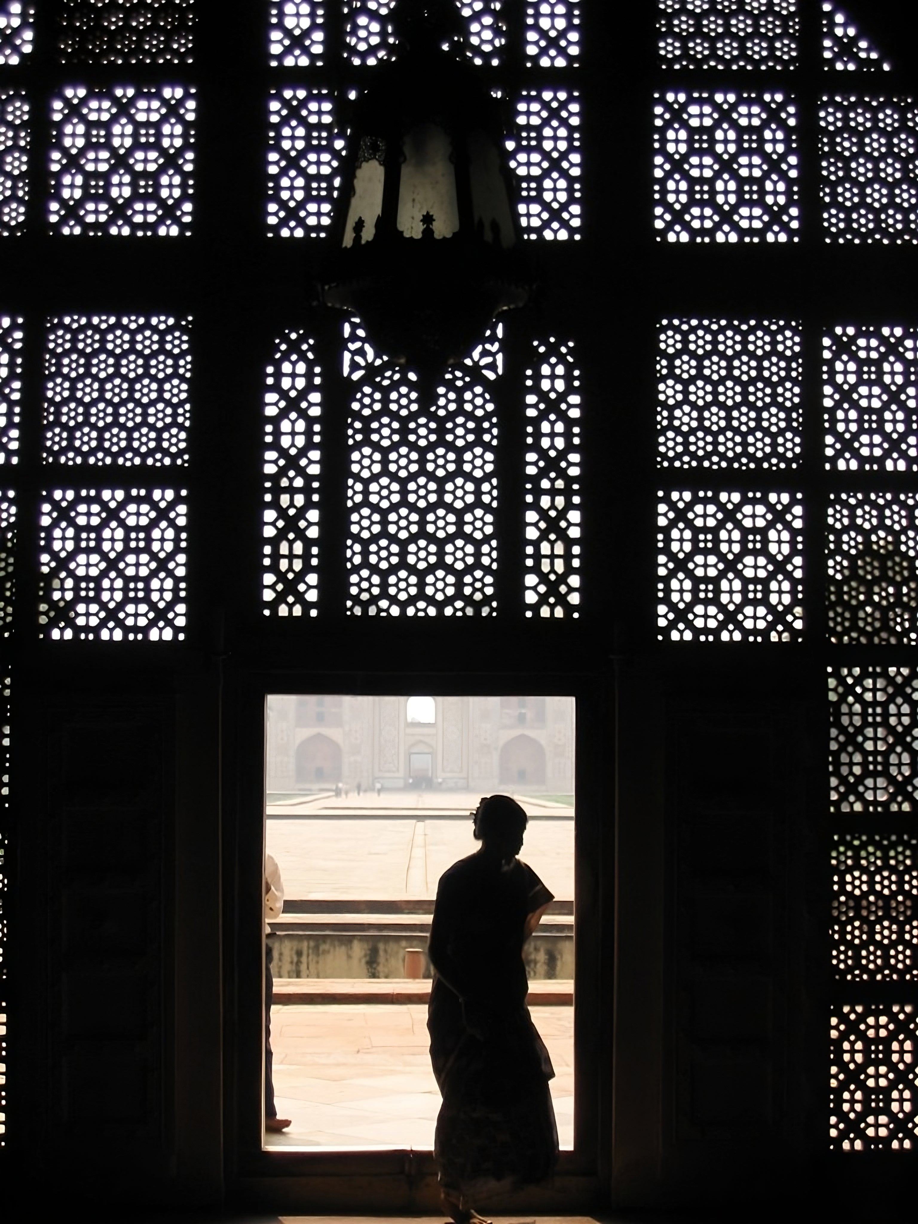 Woman entering an ornately designed building into darkness in India. 