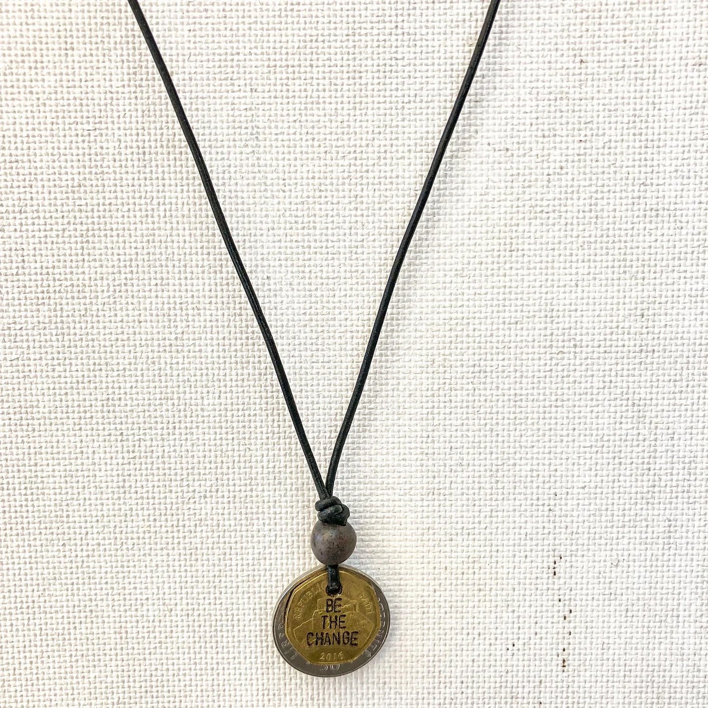 Be The Change Cord Necklace with hand-engraved Haitian Gourde coin and Papillon ceramic bead. 