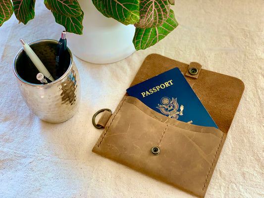 Photo of the Leather Passport Holder, showcasing the premium quality leather and multiple slots for cards and other essentials. The holder is designed to keep your passport and travel documents organized and secure, with a slim design that makes it easy to carry in your pocket or bag. The photo shows the passport holder held by a model's hand, with a focus on the intricate details and the high-quality materials used in crafting the holder.