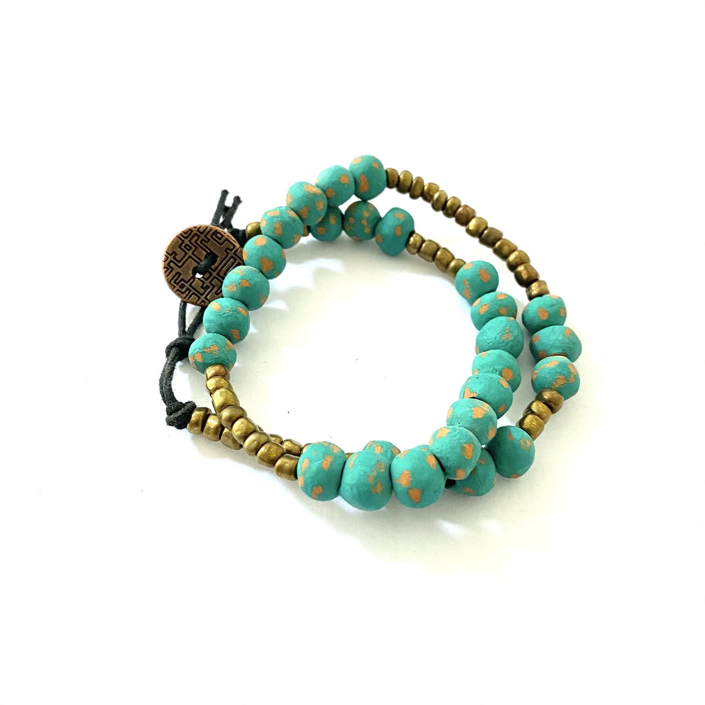 Photo of the Jovany Wrap Bracelet, showcasing the teal clay beads and smaller golden microbeads on a classic bracelet that doubles twice around the wrist. Handmade from hand-painted ceramic beads lightly distressed for a vintage feel, this timeless piece is perfect for adding a touch of elegance to any outfit. The photo shows the bracelet wrapped twice around a model's wrist, with a focus on the intricate beadwork and the coin-based clasp.